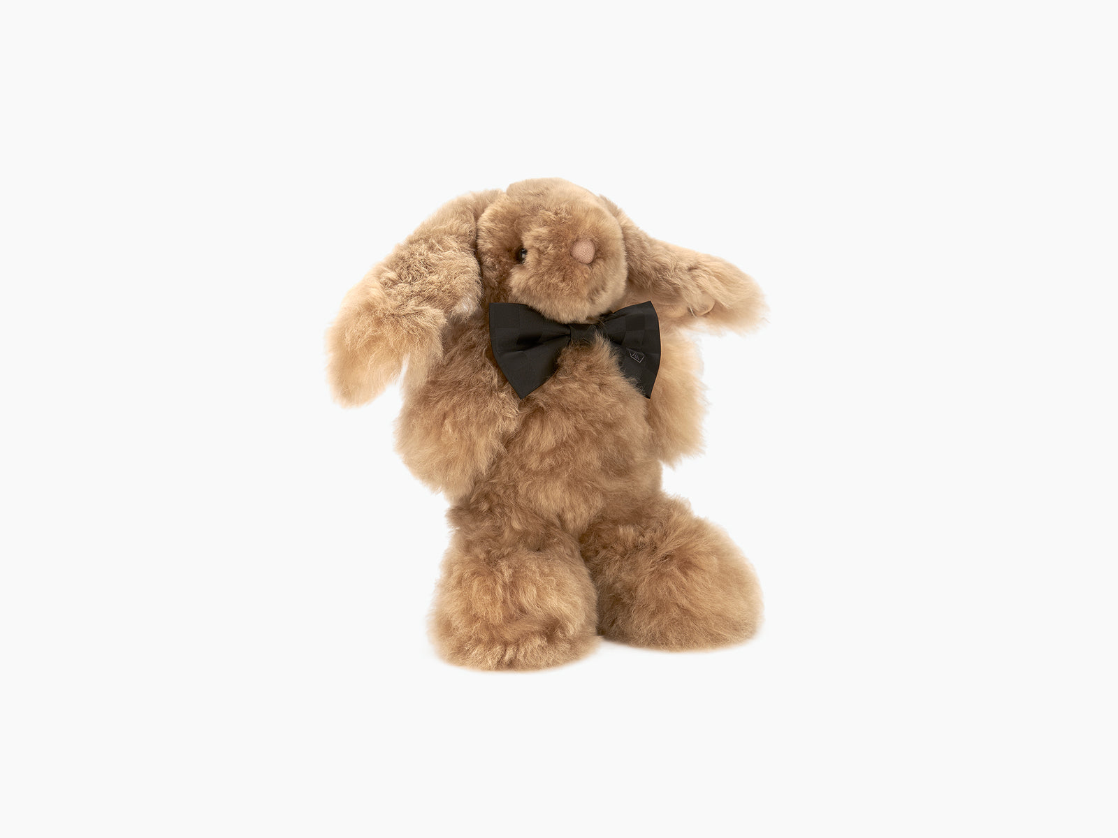 Brown plush rabbit with black bow tie posed against a white background