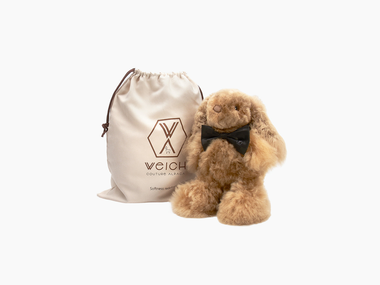 Cream Milo rabbit plush with black bow tie beside beige WEICH bag.