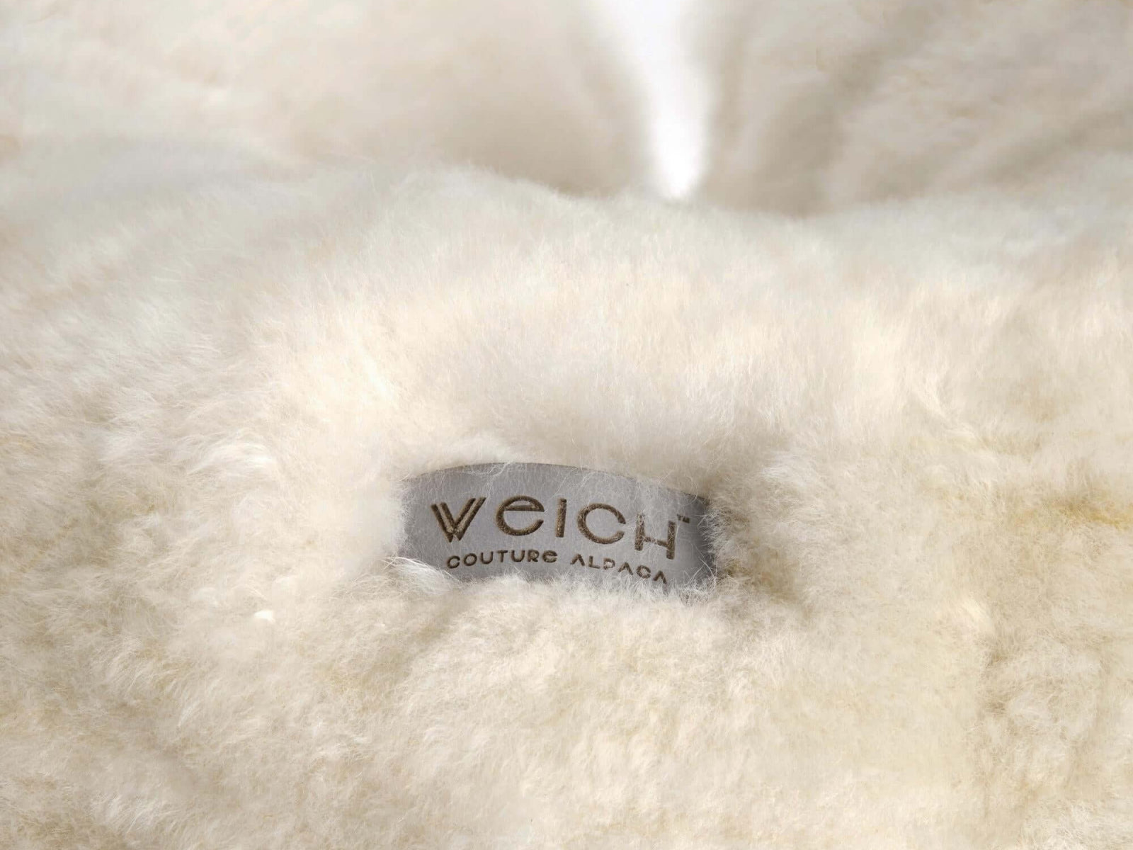 Close-up of cream alpaca fleece texture on the travel pillow showing soft fluffy fabric