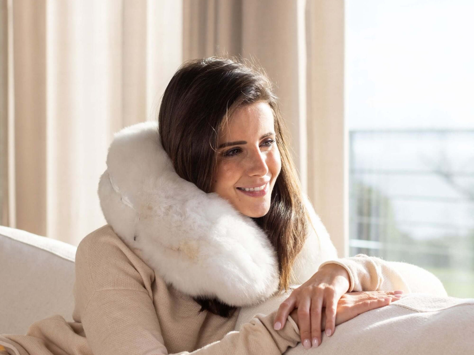 Woman relaxing with a white alpaca fiber travel pillow around her neck