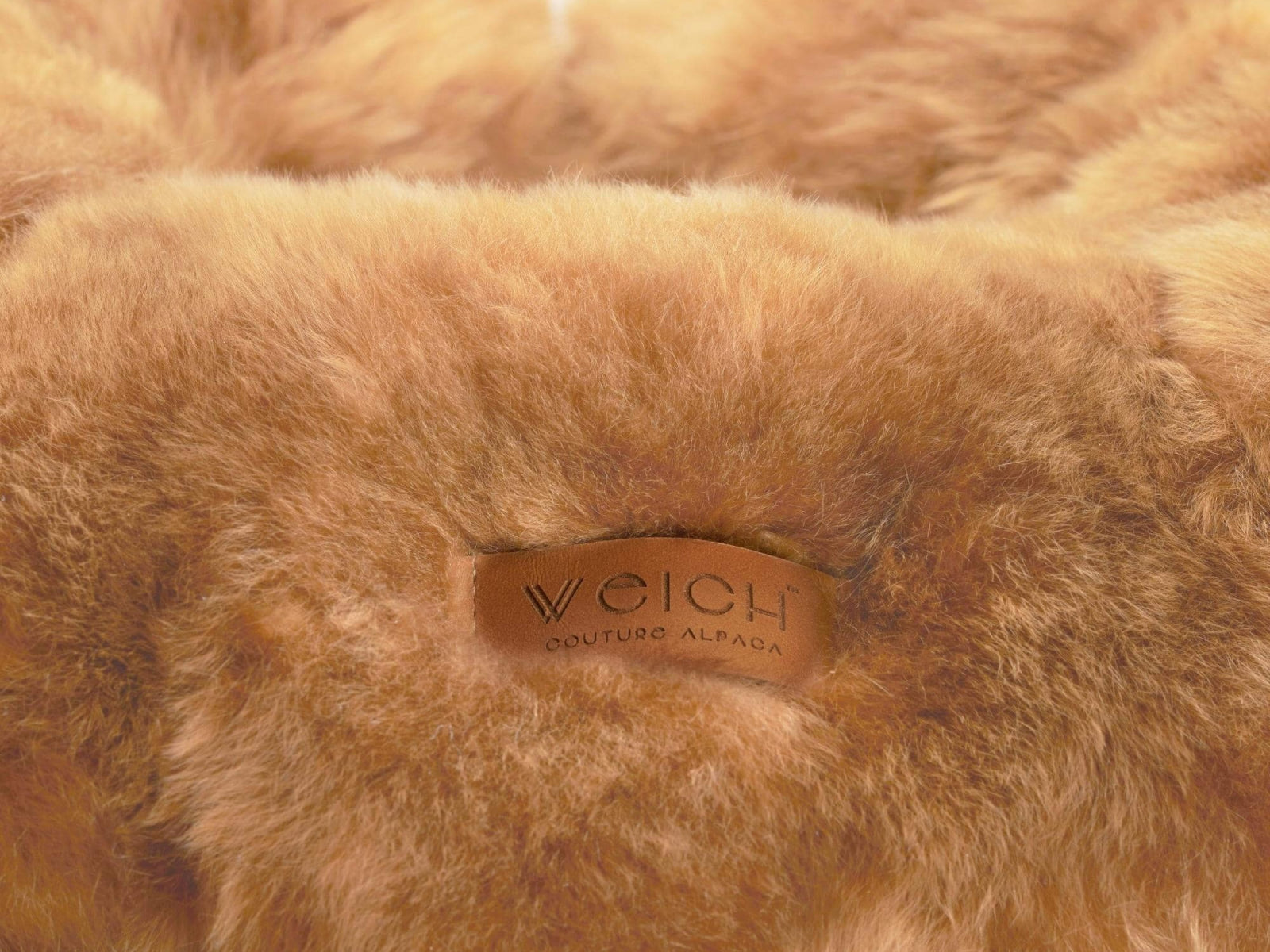 Close-up of warm brown alpaca fleece on a travel pillow with a brown leather tag