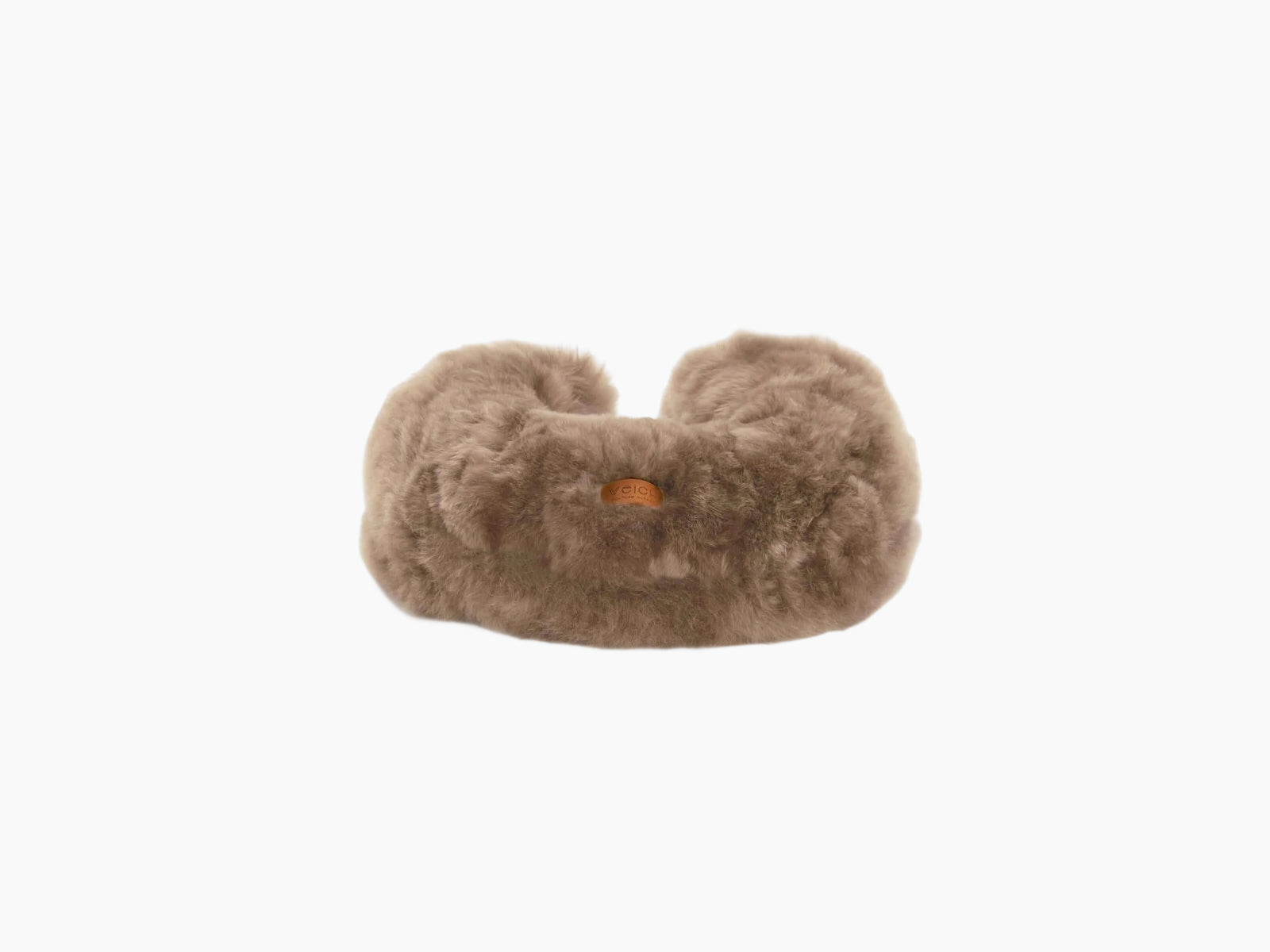 Beige plush travel pillow with alpaca fur and a small leather tag on the front