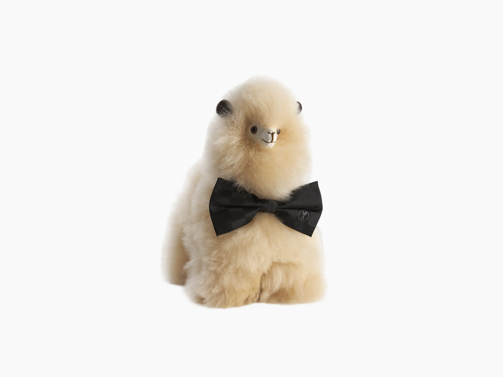 Paco plush alpaca with fluffy cream fur and a black bow tie.