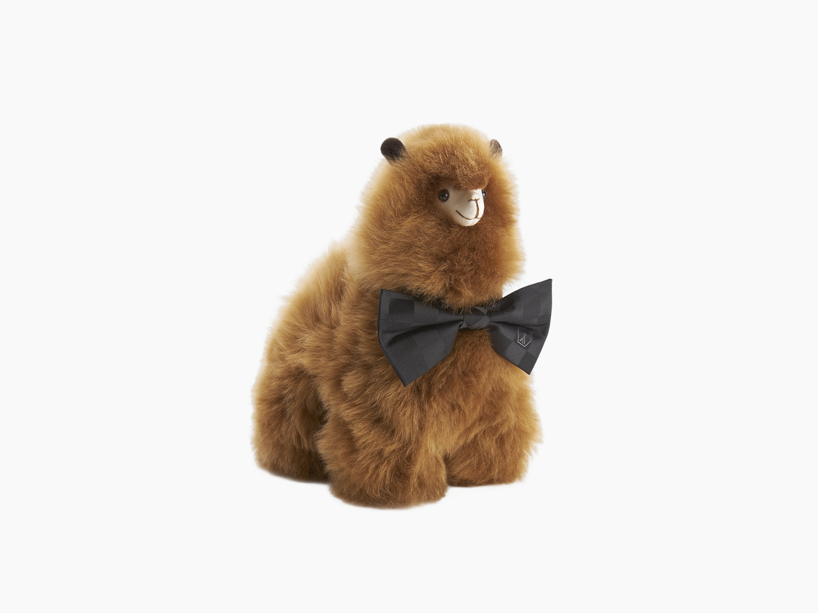 Brown fluffy Paco alpaca plush wearing a black bow tie, facing left.