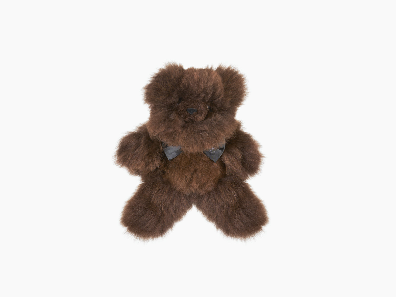 Pelu the brown teddy bear with a dark blue silk bow tie against a white backdrop