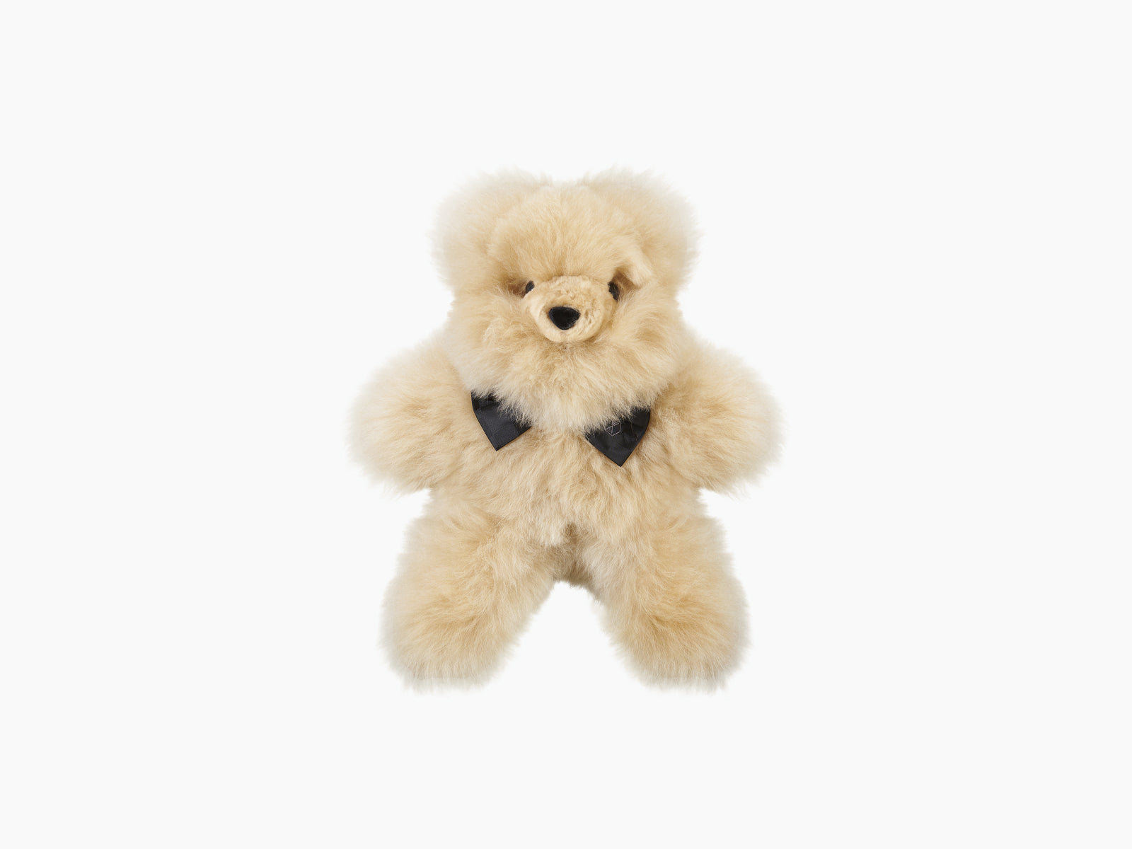 Front view of a cream fluffy Pelu teddy bear wearing a black silk bow tie