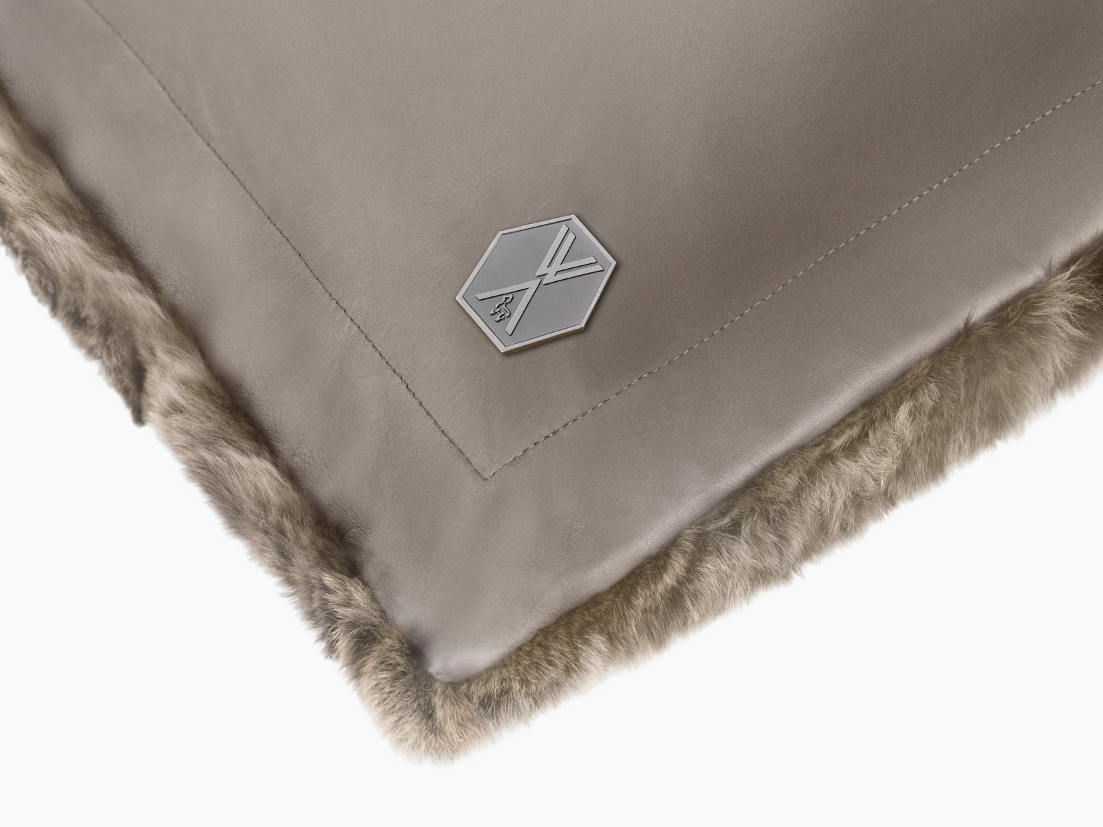 Close-up of Lounger REY showing taupe leather back plush fur front and a metal hex badge