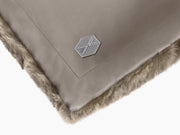 Close-up of Lounger REY showing taupe leather back plush fur front and a metal hex badge