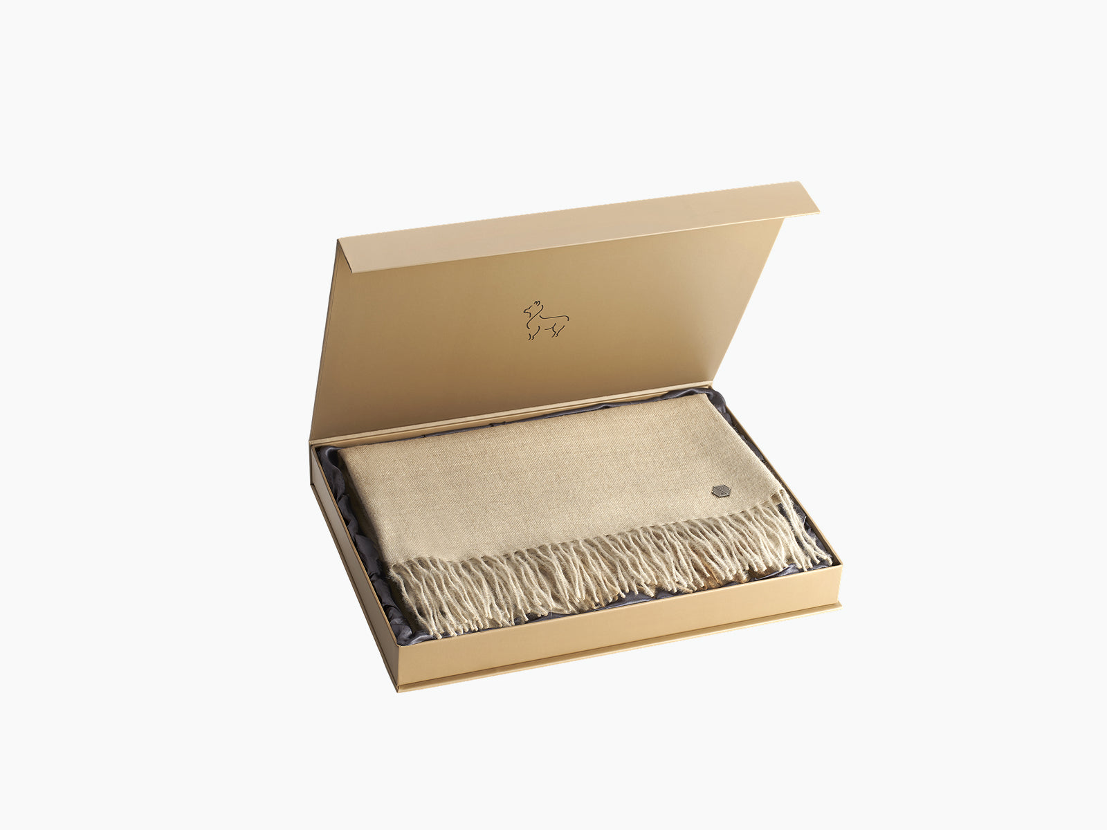 Beige fringed throw folded inside an open gold gift box
