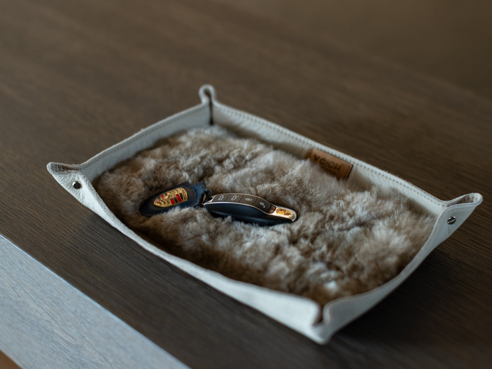 Large catchall tray with a genuine leather shell and plush alpaca lining on a wooden surface, holding keys.
