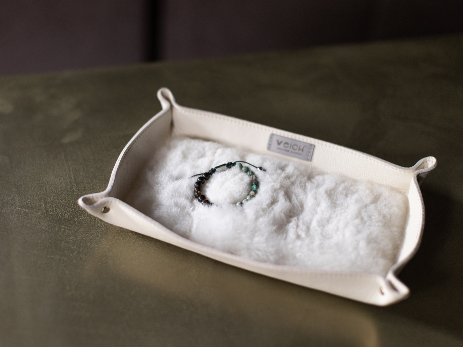 Cream alpaca fur lined catchall tray as a hand places a beaded bracelet inside