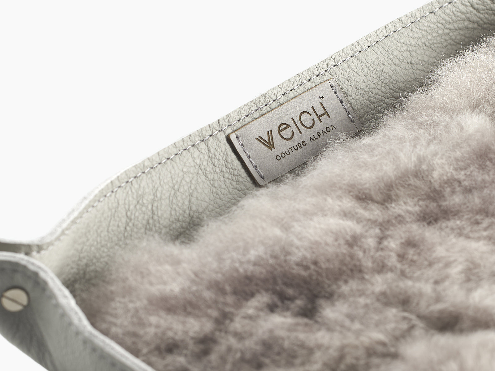 Close up of a WEICH catchall tray showing leather exterior and fluffy alpaca lining with a metal WEICH label