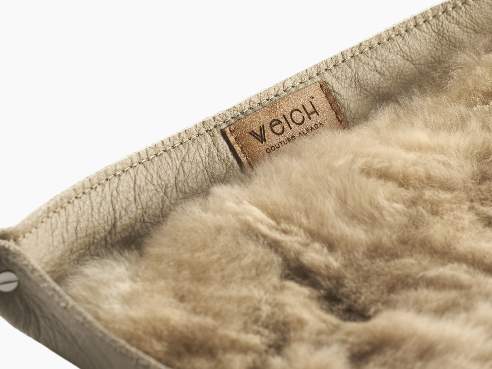 Close-up of the tray edge and plush alpaca interior with a WEICH tag