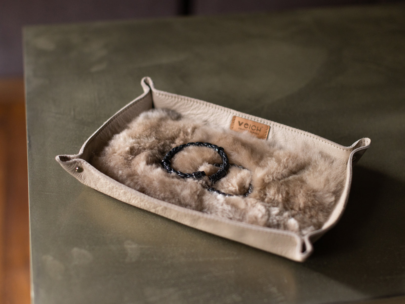 Cream leather catchall tray lined with plush fur displaying beaded bracelets