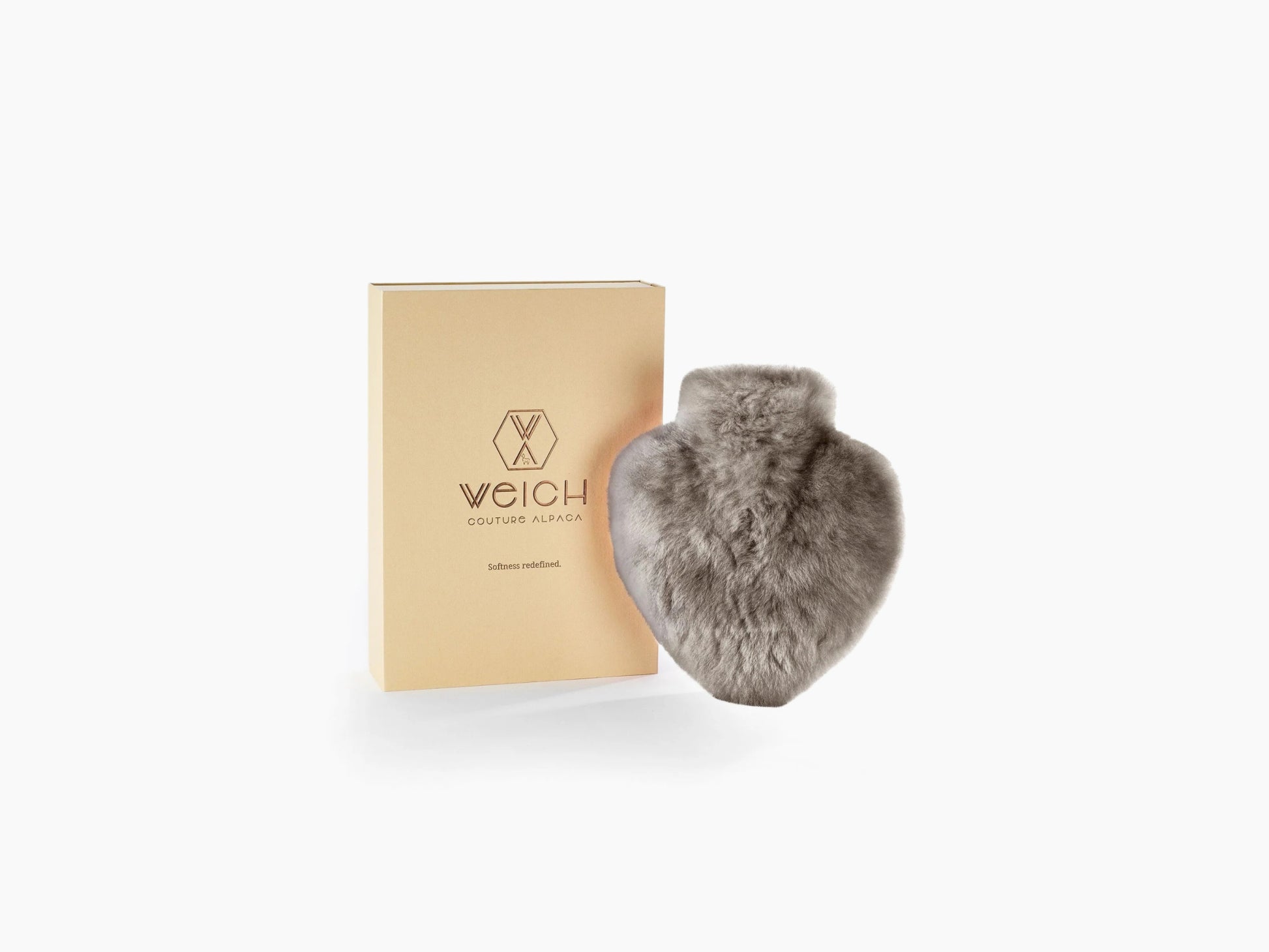 Gray heart shaped alpaca hot water bottle beside a beige WEICH gift box.