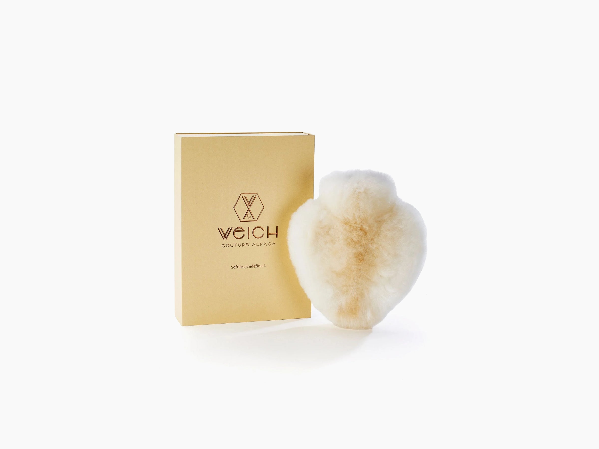 Cream colored heart shaped alpaca hot water bottle beside a beige WEICH gift box.